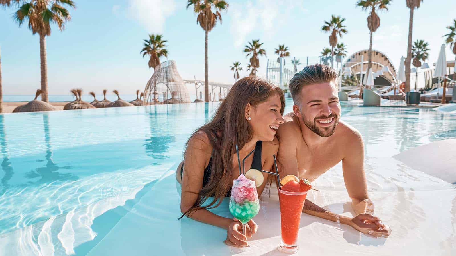 Young couple on infinity pool cocktails From Classic to Creative: Inspiring Honeymoon Ideas for Newlyweds