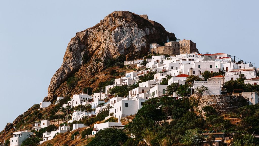 White buildings seemingly climb a rocky mountain in Chora, Skyros.